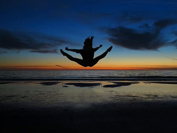 Daughter doing jump, sunset, Santa Monica beach